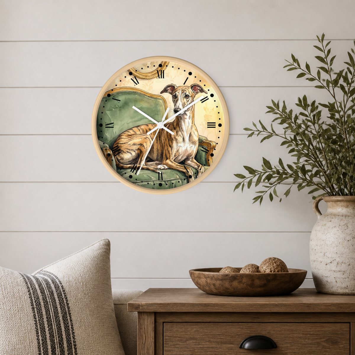 A round wall clock with a vintage-style illustration of a greyhound dog on the face, mounted on a white shiplap wall above a wooden side table with a plant and decorative bowl.