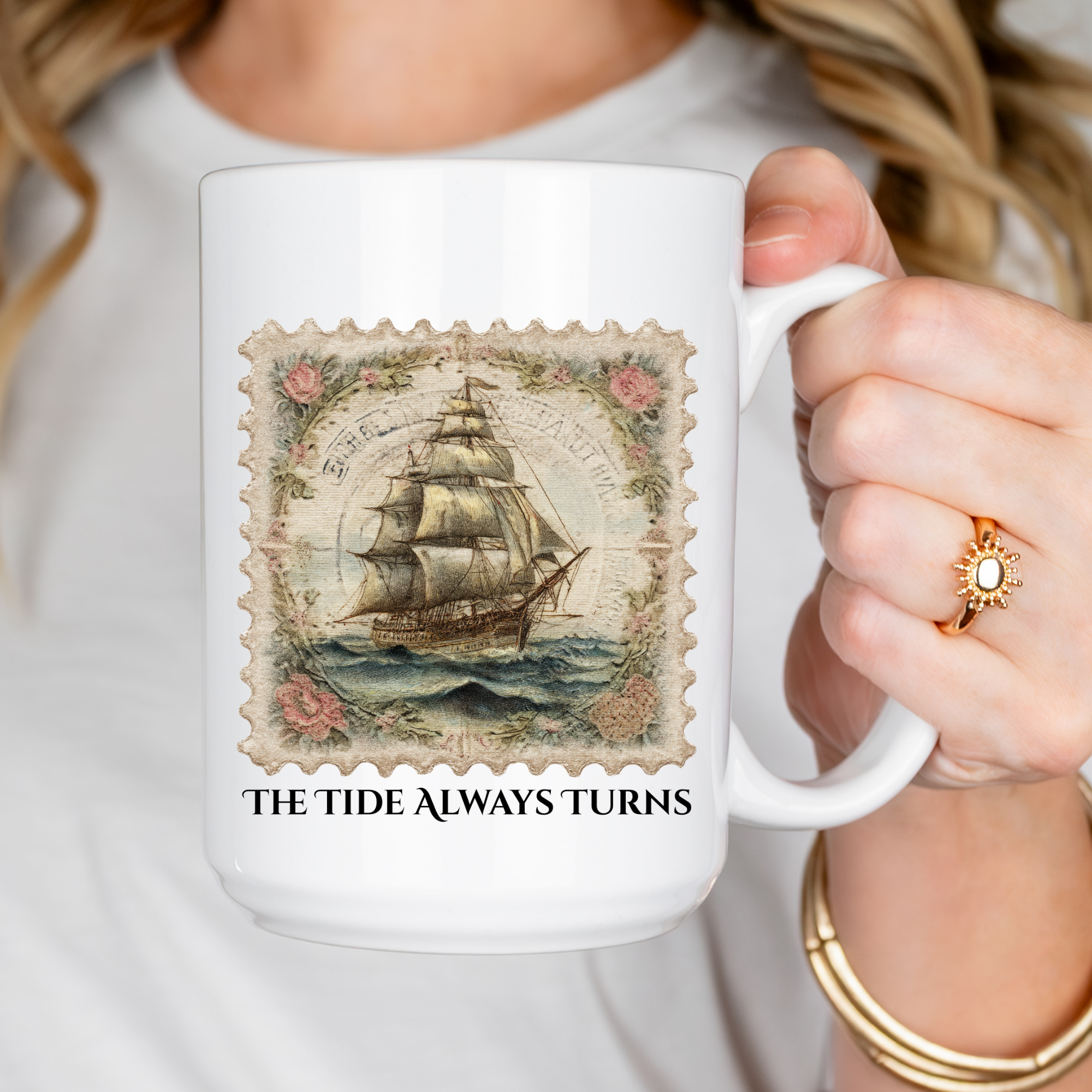 White mug with ship design and 'The Tide Always Turns' text held by a person.