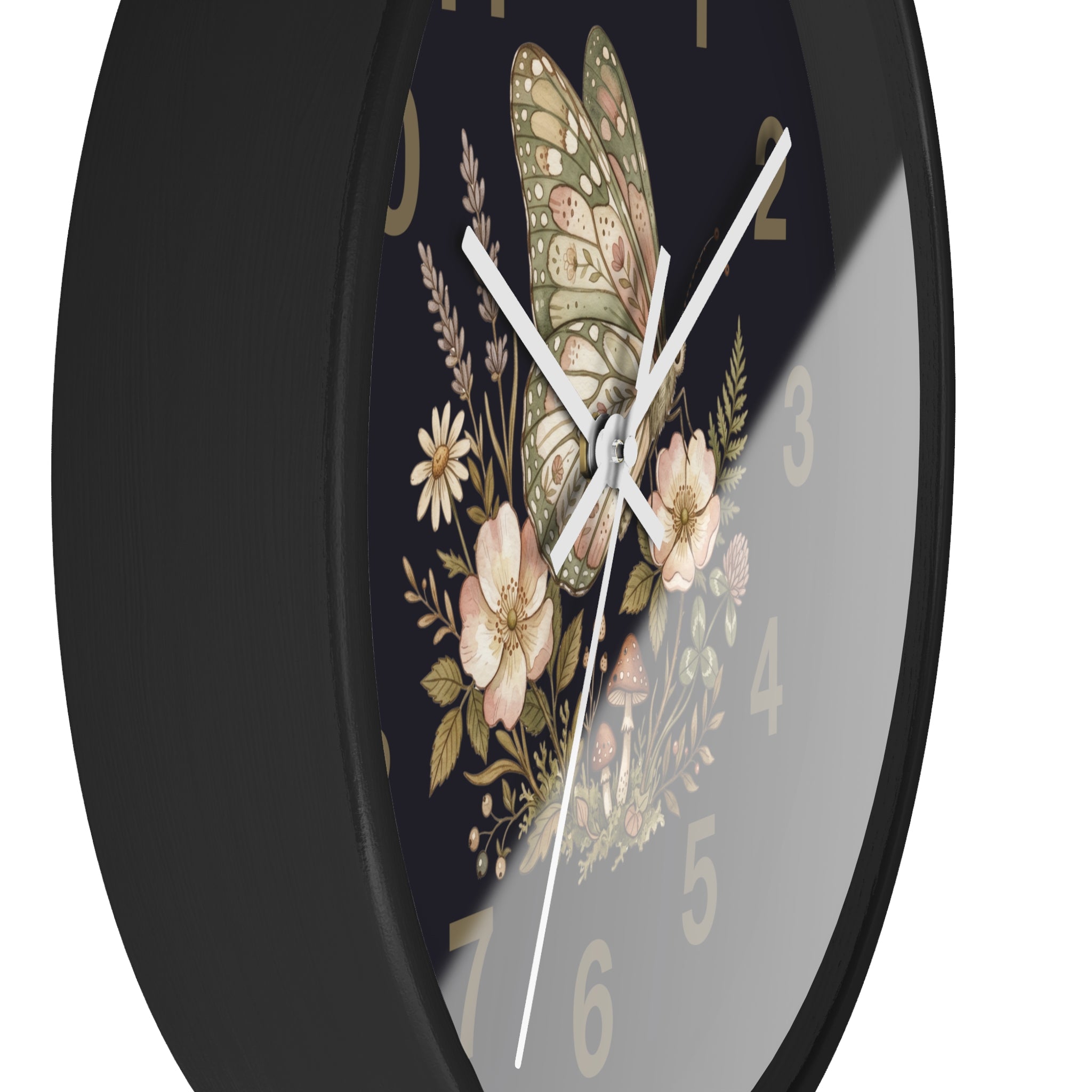 Side view of a round black wall clock with white hands and butterfly and floral design on a black background