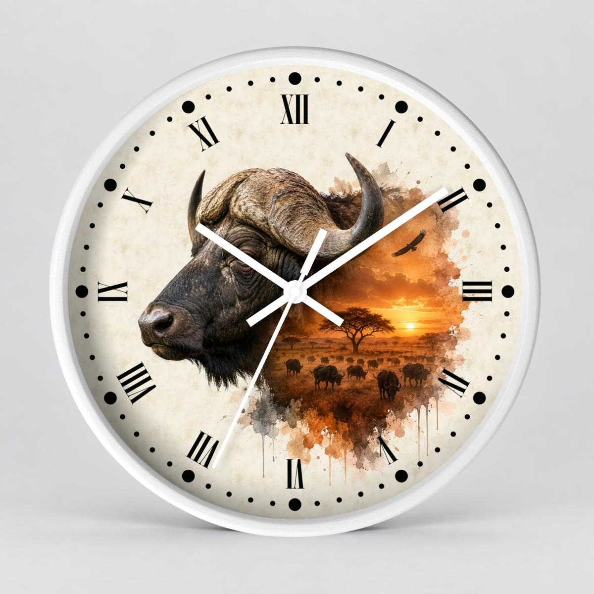 A round wall clock with a white frame and a printed safari design on the face. The artwork shows a close-up of a buffalo head on the left and an orange sunset landscape with small animals on the right.