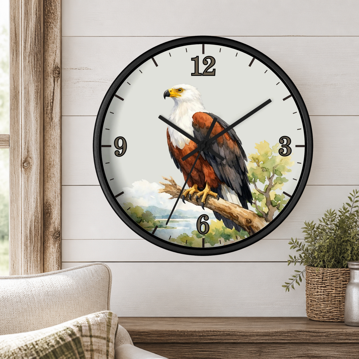 A round wall clock with a black frame and a printed eagle illustration on the face, mounted on a white shiplap wall above a wooden mantel with a small plant.