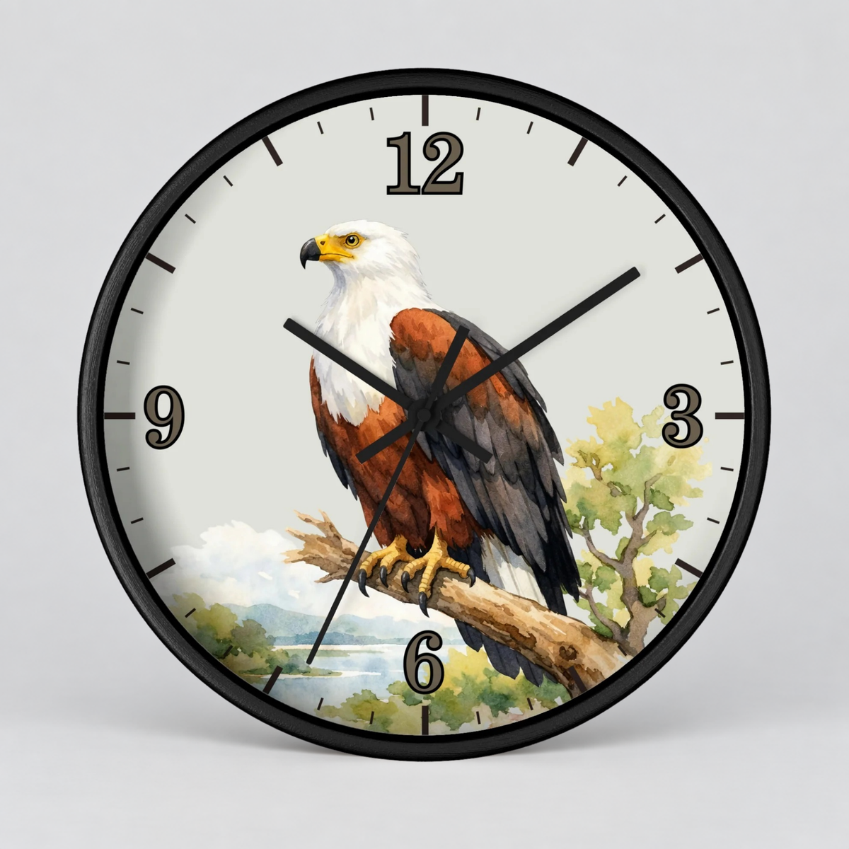 A round wall clock with a black frame and a printed design of a fish eagle perched on a branch against a light sky and water background. The clock face has black Arabic numerals and black clock hands.