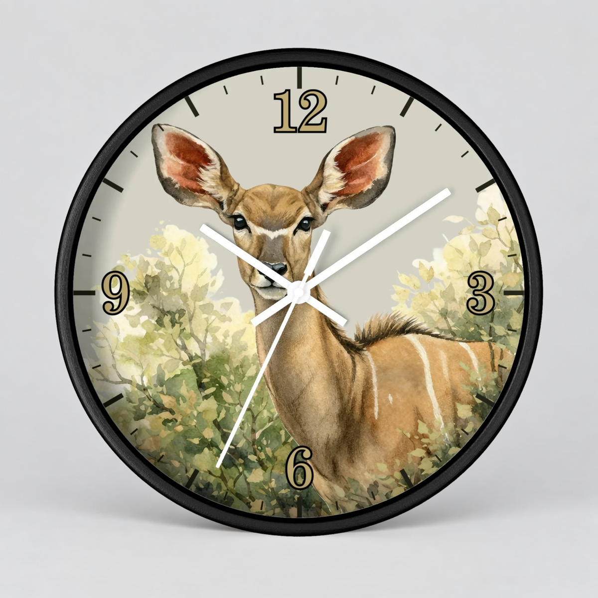 A round wall clock with a black frame and a printed illustration of a kudu deer among pale green and cream flowers on the clock face. The numbers 1 through 12 are visible, along with white clock hands and a black outer rim, shown against a light gray background.