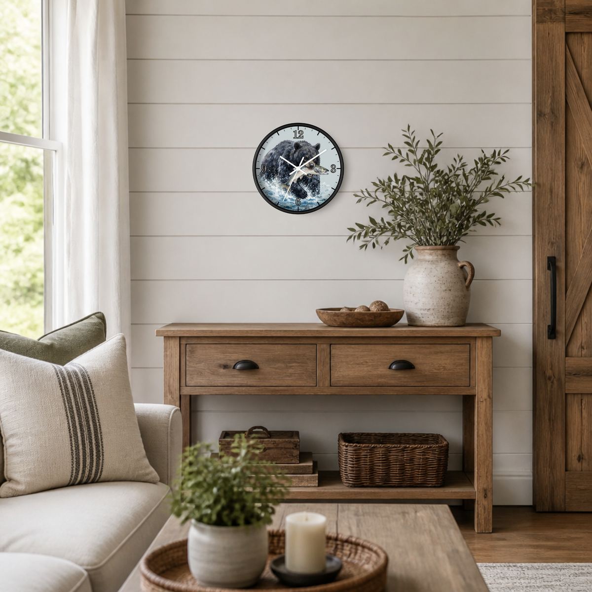 A round wall clock with a black bear illustration hangs on a white shiplap wall above a rustic wooden console table in a bright, modern farmhouse-style living room.