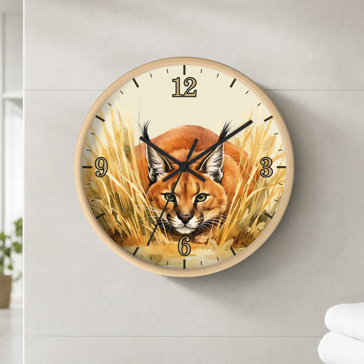 Round wall clock with a natural wood frame and a printed illustration of a lynx cat in tall golden grass. The clock face has black Arabic numerals and black clock hands, and it is mounted on a light gray wall.