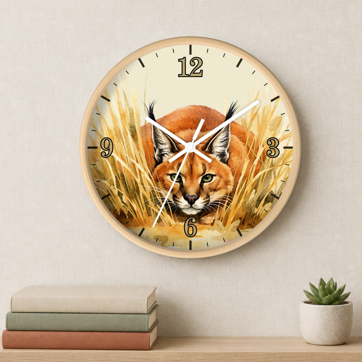 Round wall clock with a natural wood frame and a printed design of a caracal in golden grass, mounted on a light beige wall above a shelf with books and a small succulent.