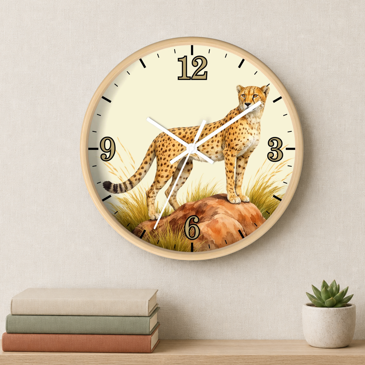 Round wall clock with a cheetah illustration on the face, mounted on a light beige wall above a shelf with stacked books and a small potted succulent.