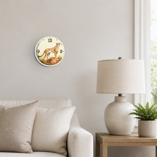A round wall clock with a cheetah cat illustration hangs on a light gray wall above a beige sofa. A white table lamp sits on a wooden side table next to a potted fern, with a window visible on the right.