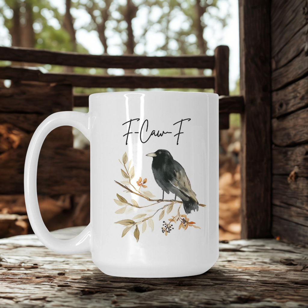 White mug with a bird illustration and 'F-Caw F' text on a wooden surface.