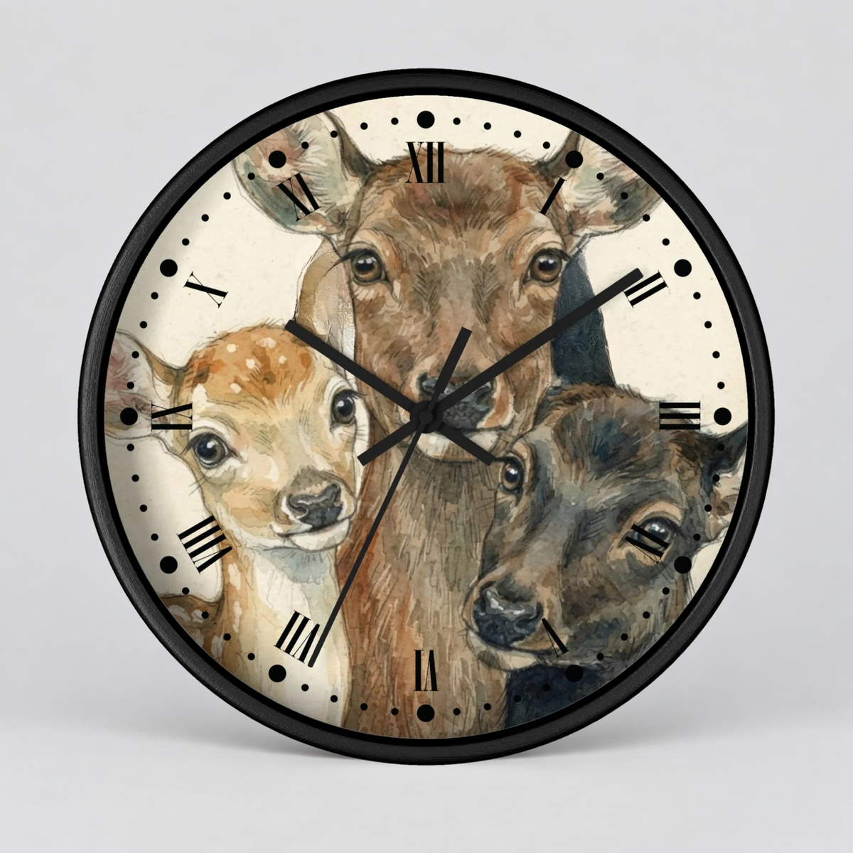A round wall clock with a black frame and a printed illustration of three deer heads on the face. The clock has black Roman numerals and black hands, photographed against a light gray studio background.
