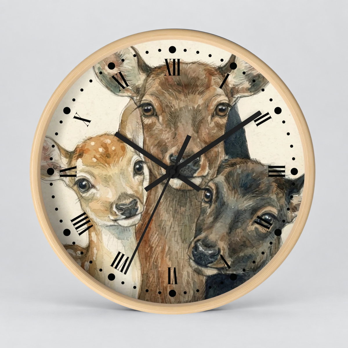 Round wall clock with a light wood frame and a printed illustration of three deer heads on the clock face, with black Roman numerals and black clock hands, shown against a light gray background.