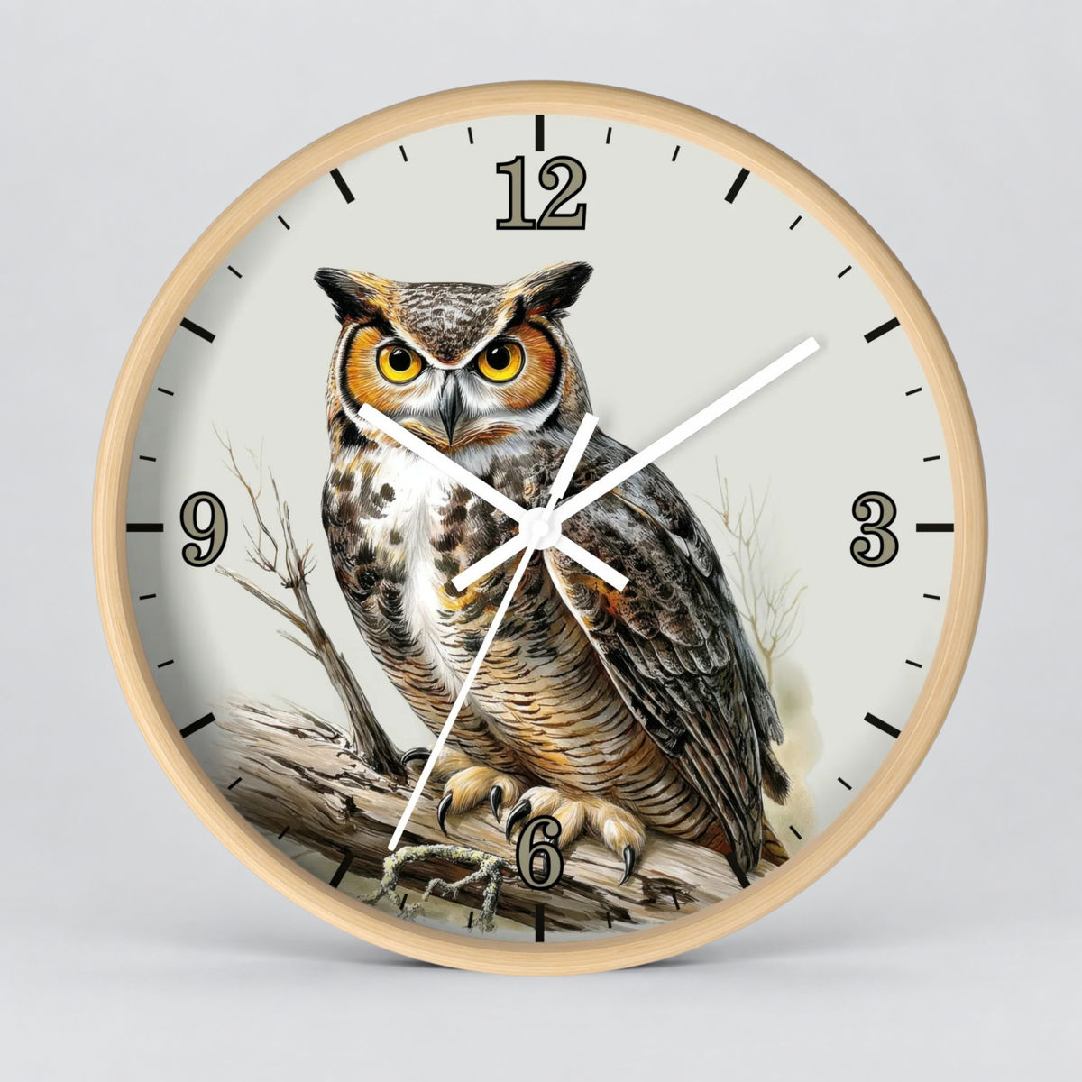 A round wall clock with a light natural wood frame and a detailed illustration of a large owl on the face. The clock has black Arabic numerals and white hands against an off-white background, photographed on a neutral light gray studio backdrop.