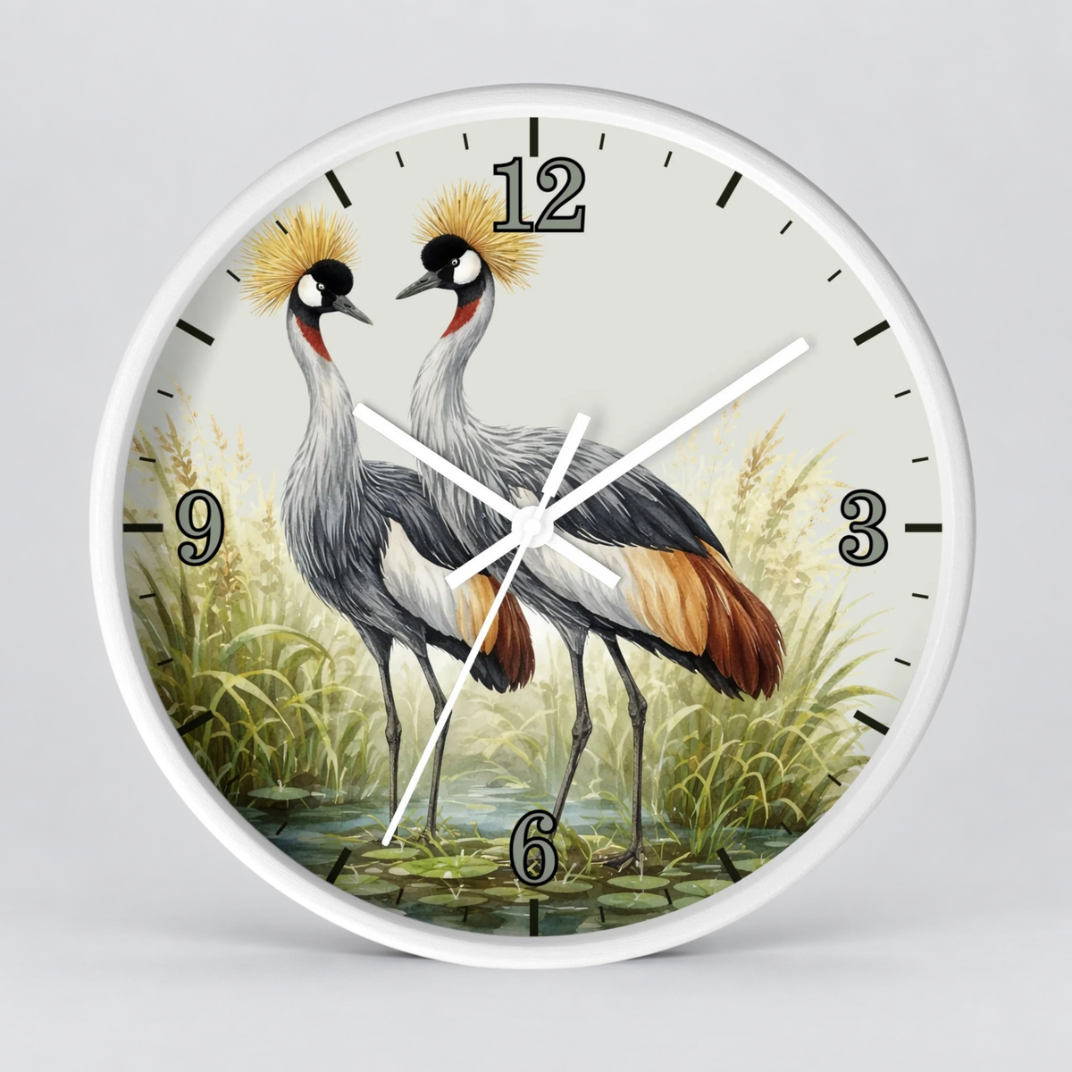 A round wall clock with a white frame and a printed illustration of two crowned cranes standing in a marsh. The clock face has black Arabic numerals and black hour markers, with white hands on a light gray background.