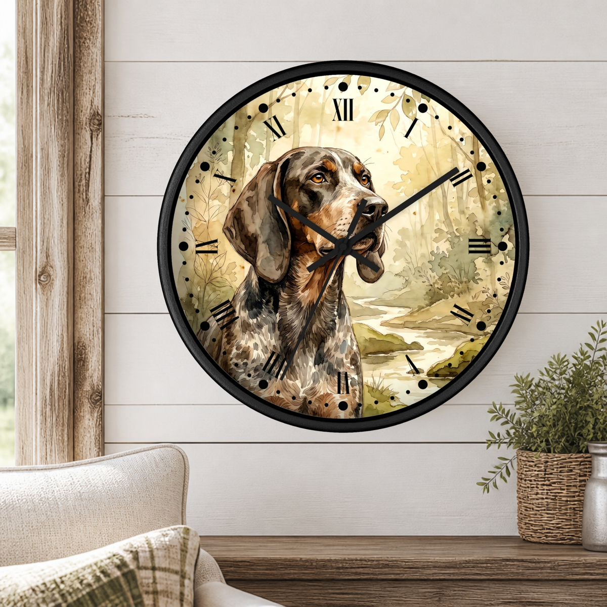 Round wall clock with a black frame and a printed illustration of a brown and white dog in a forest setting, mounted on a white shiplap wall above a wooden table with a plant.