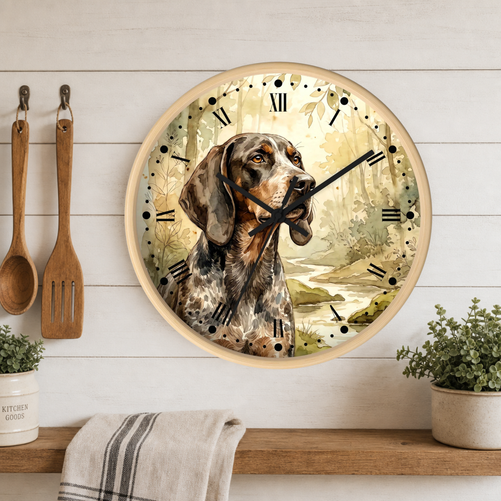 A round wall clock with a wood-grain frame and a printed illustration of a hunting dog over a forest scene, mounted on a white wood-paneled wall above a shelf with kitchen utensils and plants.