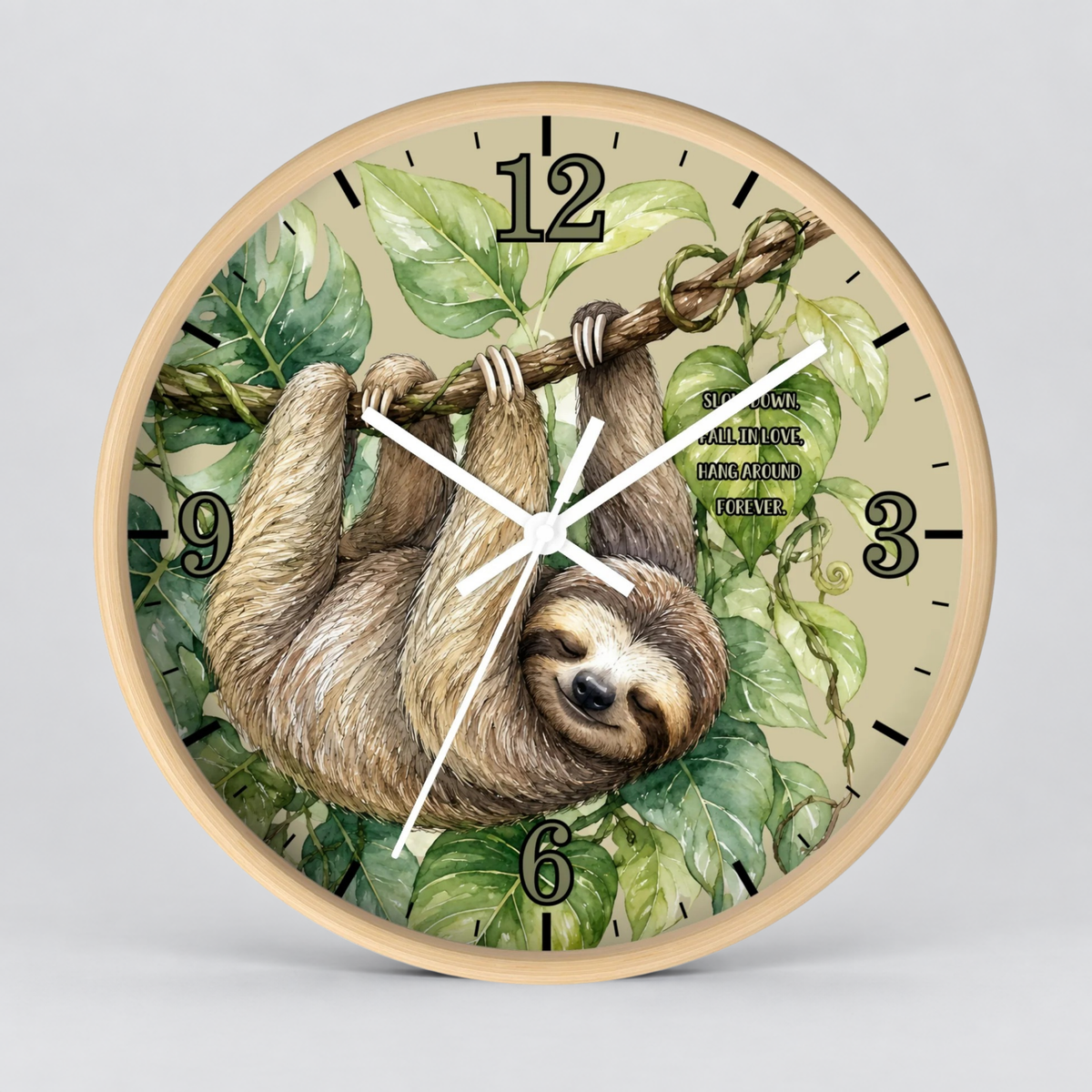 Round wall clock with a light wood frame and a printed illustration of a sloth hanging from a tree branch among green leaves. The clock face is light beige with black Arabic numerals and white hands, shown against a neutral gray background.