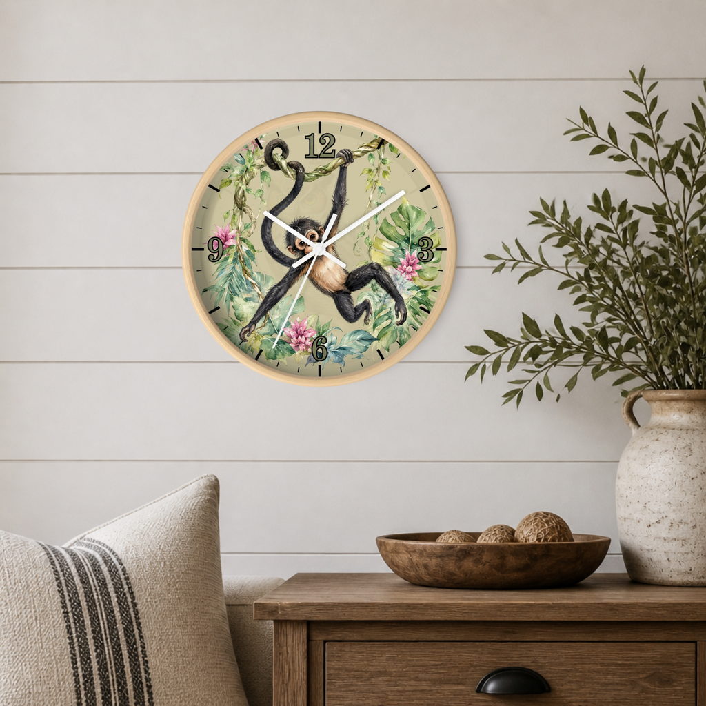 A round wall clock with a natural wood frame hangs on a white shiplap wall above a wooden side table. The clock face features a vintage-style illustration of a brown monkey hanging among green leaves and pink flowers, with black Arabic numerals.