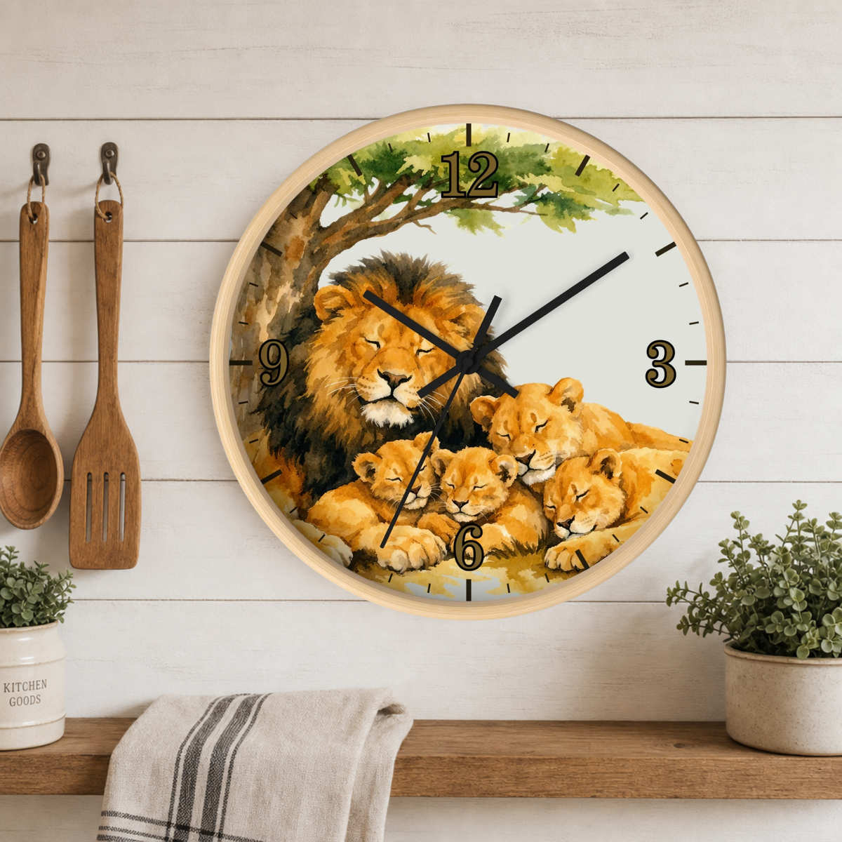 A round wall clock with a natural wood frame hangs on a white wood-paneled wall above a shelf. The clock face features a painted family of lions under a tree.