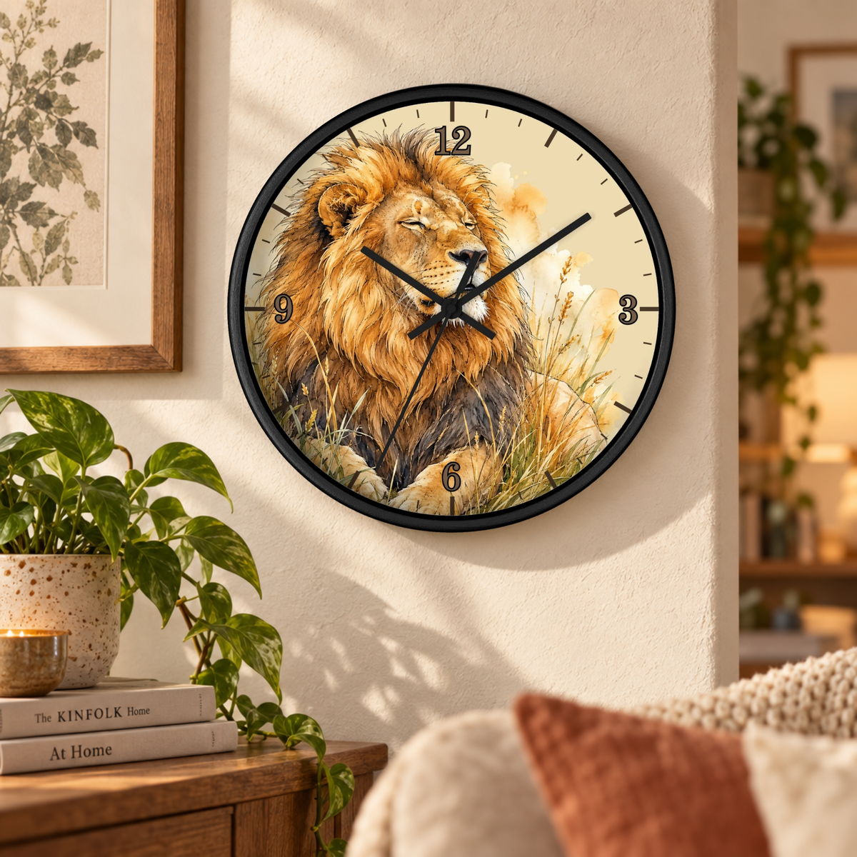 A round wall clock with a black frame and a printed lion illustration on the face, mounted on a cream wall in a styled living room setting with a plant, books, and furniture visible.