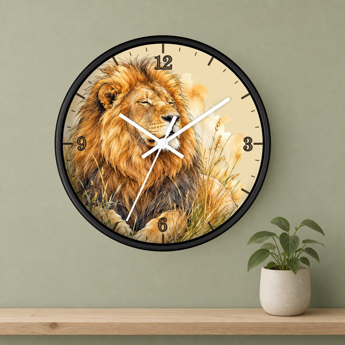 A round wall clock with a black frame and a printed lion illustration, mounted on a sage green wall above a wooden shelf with a small potted plant.