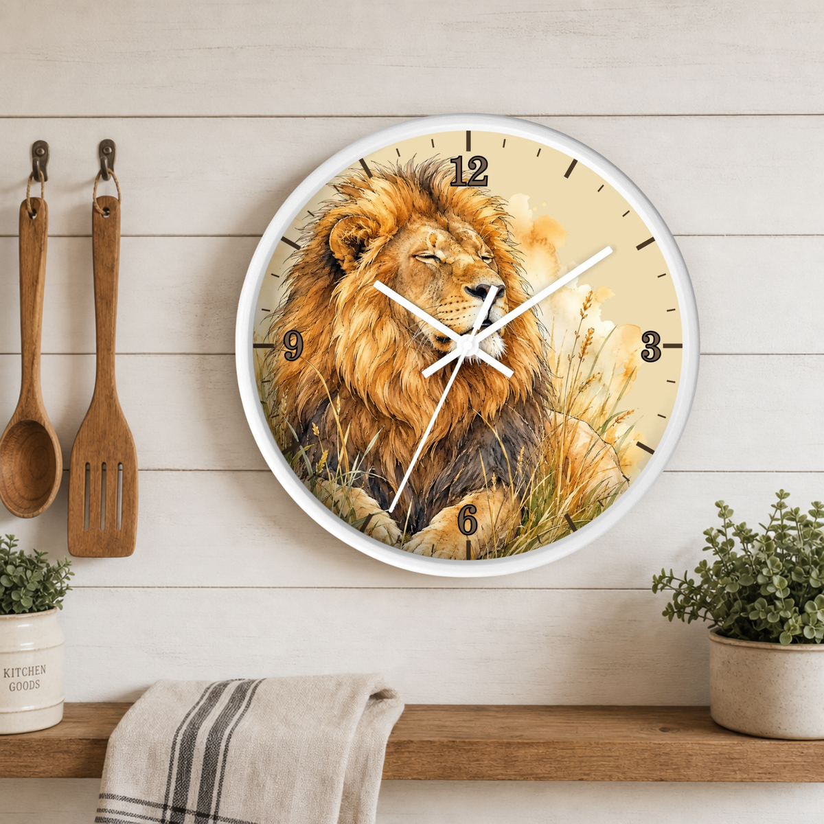 A round wall clock with a white frame and a printed lion illustration on the face, mounted on a light wood plank wall above a shelf with small plants and kitchen utensils.