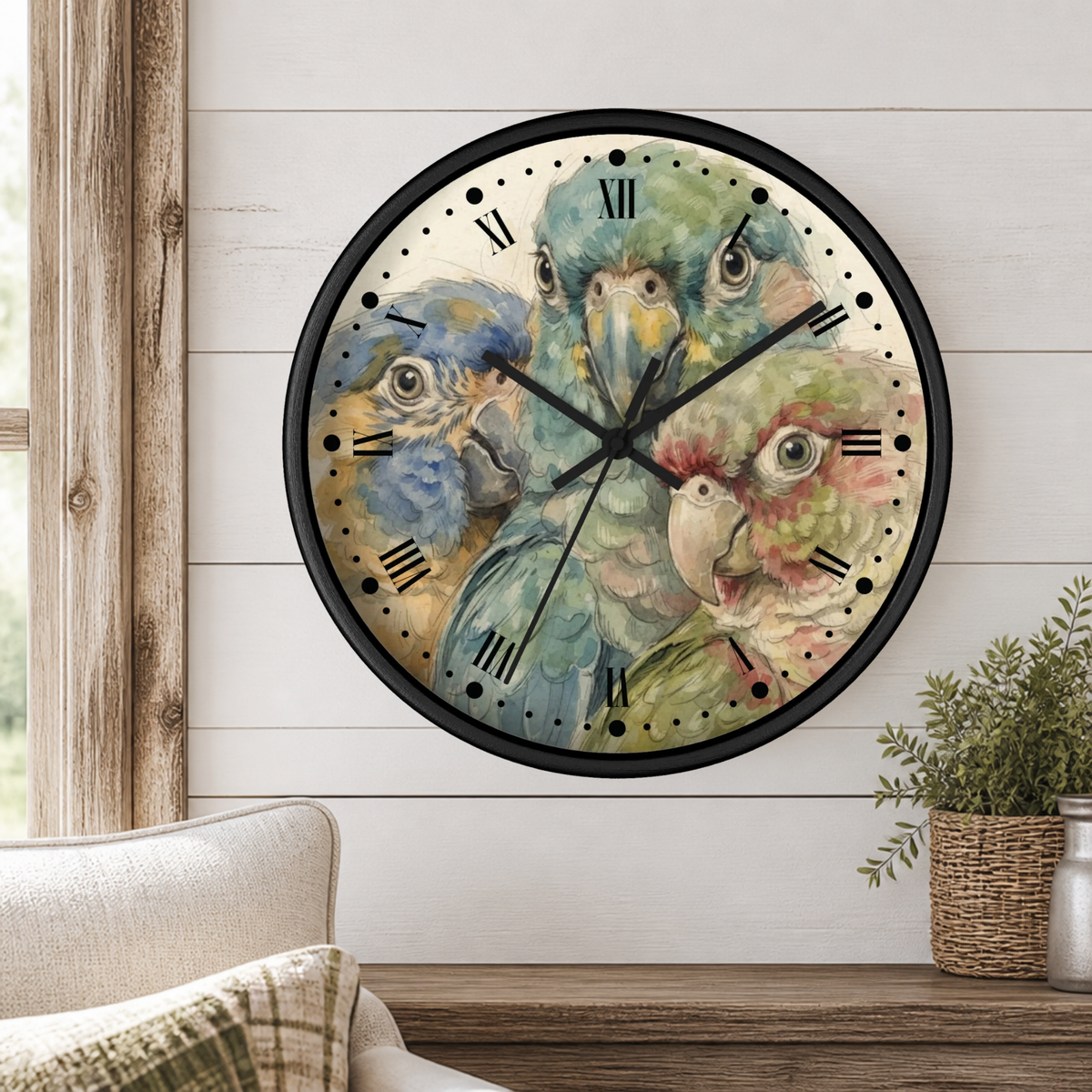 A round wall clock with a black frame and a watercolor-style parrot illustration on the face, mounted on a white shiplap wall above a wooden mantel with a small plant and part of a sofa visible.