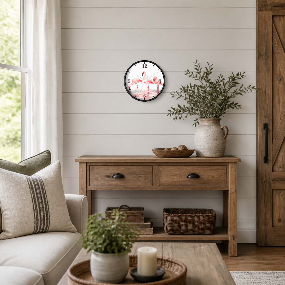 A round wall clock with a black frame and a floral clock face hangs on a white shiplap wall above a rustic wooden console table in a bright, modern farmhouse living room.