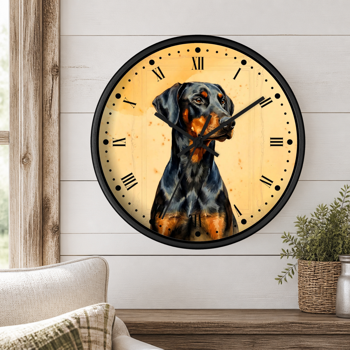 A round wall clock with a black frame and a printed portrait of a black-and-tan dog on a warm cream face, mounted on a white shiplap wall above a wooden shelf with a plant and part of a chair visible.