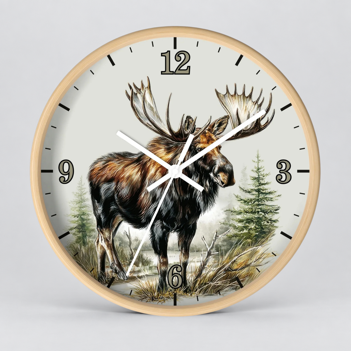 Round wall clock with a light natural wood frame and a detailed illustration of a moose in a forest on the clock face, with black Arabic numerals and white clock hands, shown against a neutral gray background.