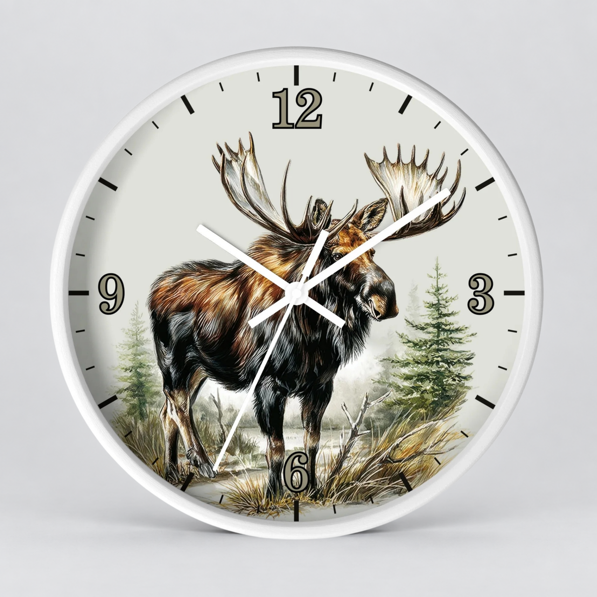 A round wall clock with a white frame and a detailed illustration of a moose standing in a forest on the clock face, with black Arabic numerals and white hands against a light gray background.