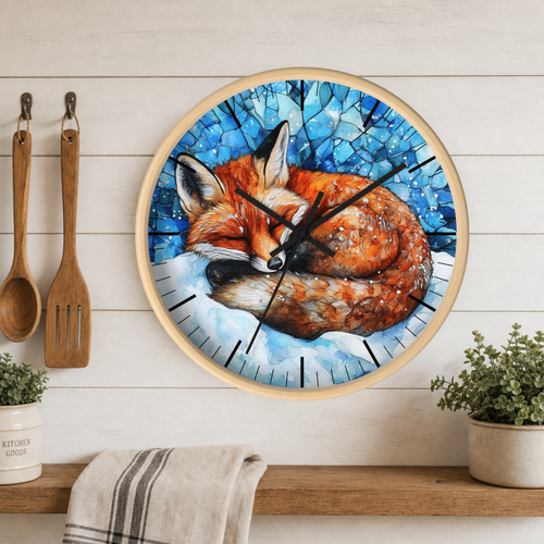 A round wall clock with a light wood frame hangs on a white wood-paneled wall above a shelf. The clock face features a painted sleeping fox in orange and brown tones against a blue mosaic-style background.