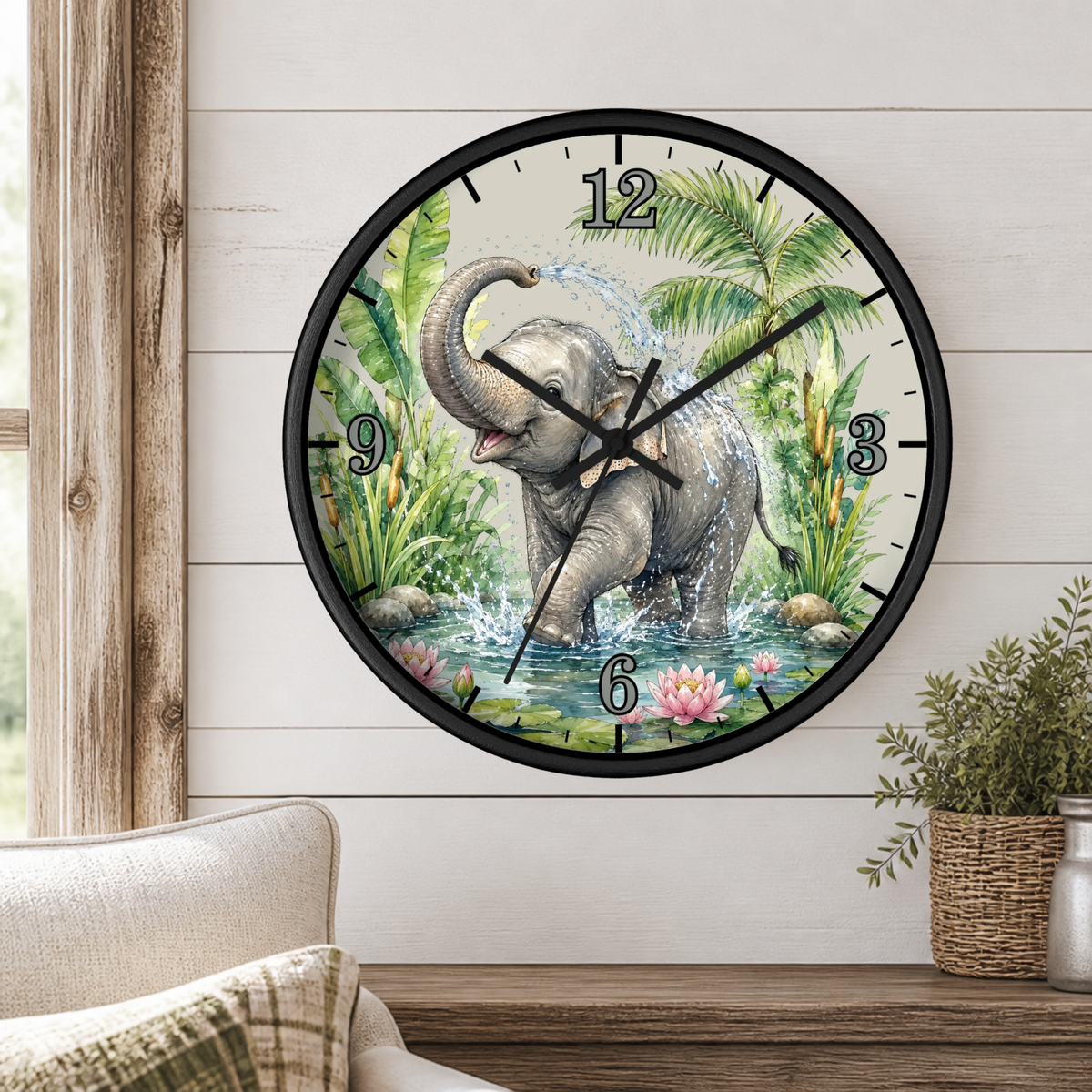 A round wall clock with a black frame and a printed elephant bathing in water scene on the face, mounted on a white shiplap wall above a wooden console table with a chair and potted plant.