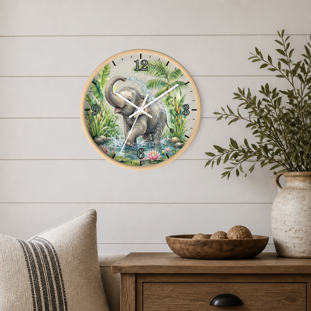 A round wall clock with a light wood frame hangs on a white shiplap wall above a wooden side table. The clock face features a detailed illustration of an elephant standing in water with palm trees and tropical foliage.