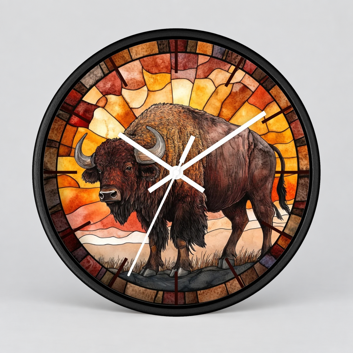 A round wall clock with a stained-glass-style design featuring a brown bison standing in front of warm orange, yellow, and brown geometric panels. The clock has a black frame and white hands, shown on a light gray background.