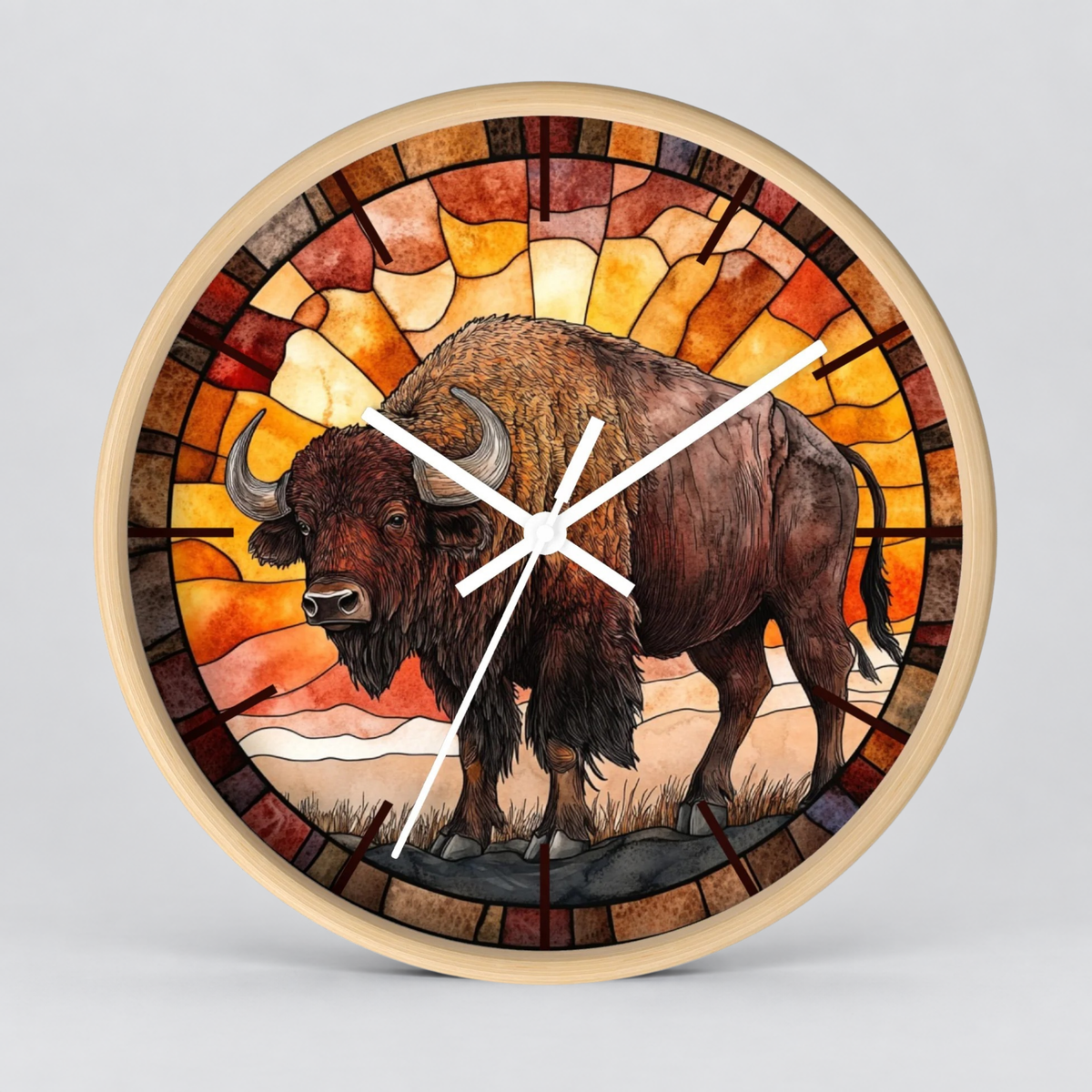 Round wall clock with a stained-glass-style design featuring a brown bison in front of warm orange and yellow geometric sunburst panels, with white clock hands and a light wood-toned rim, shown on a light gray background.
