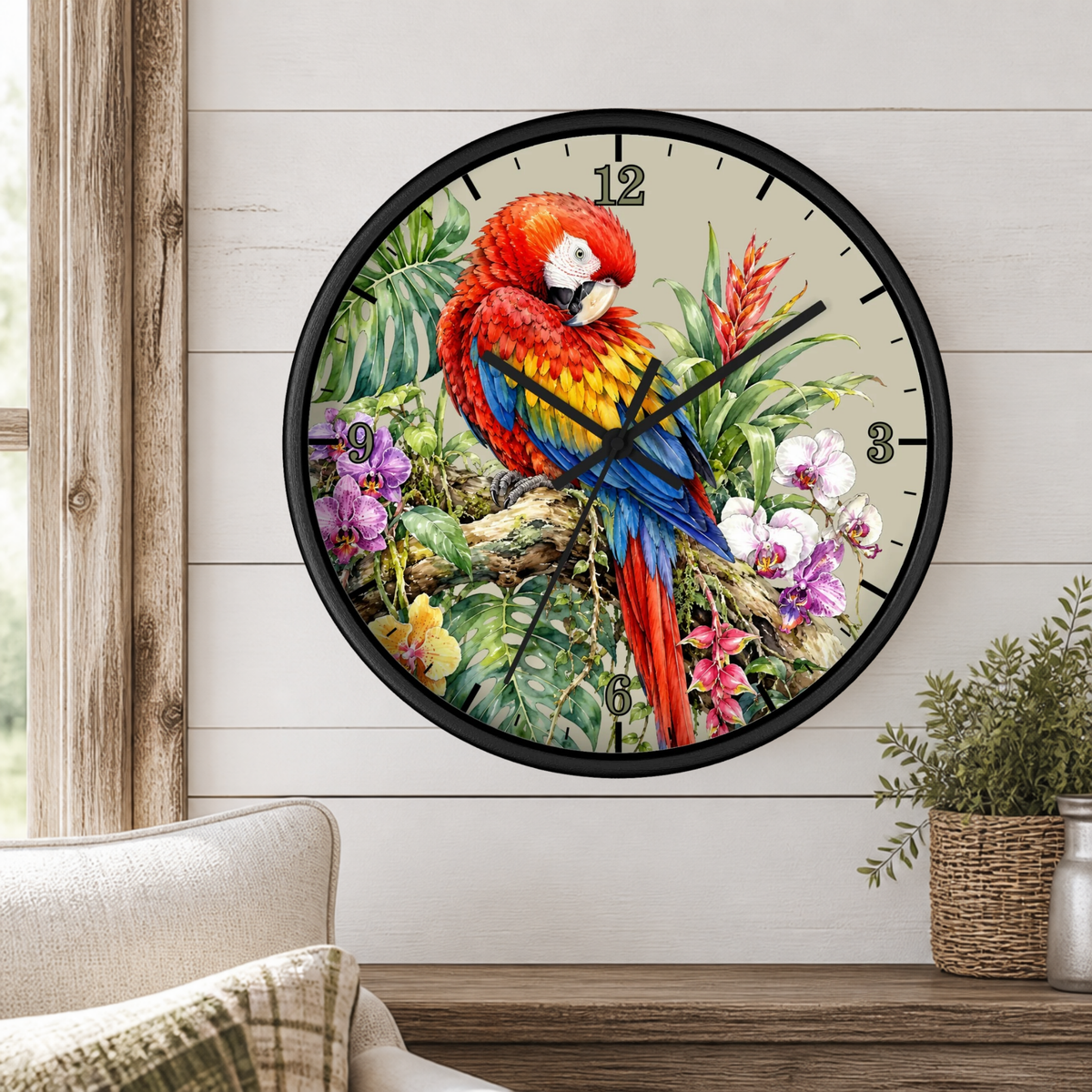 A round wall clock with a black frame and a colorful parrot illustration, mounted on a white wood-paneled wall above a wooden shelf with a small potted plant.