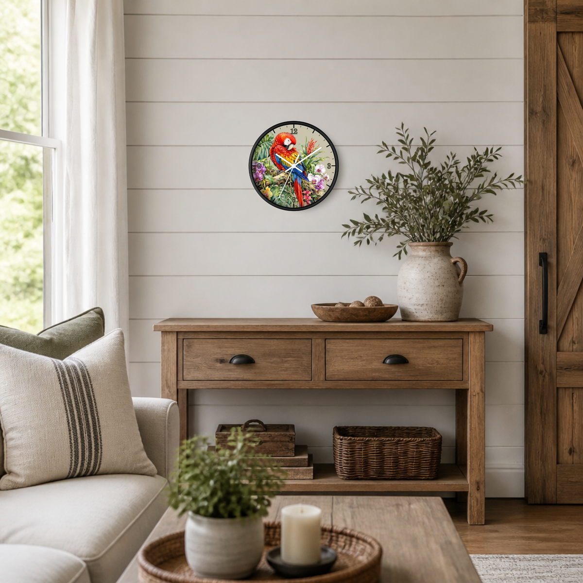 A round wall clock with a rustic botanical illustration hangs on a white shiplap wall above a wooden console table in a styled living room setting.