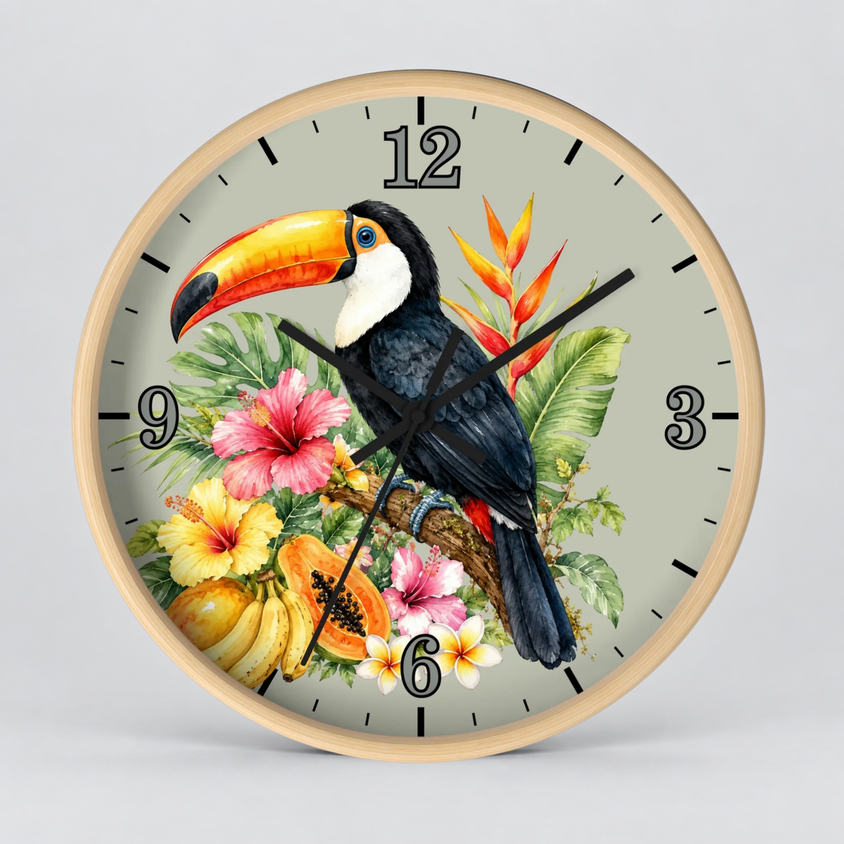 A round wall clock with a light wood frame and a tropical design featuring a black-and-white toucan, colorful flowers, bananas, papayas, and green leaves on a pale gray background.