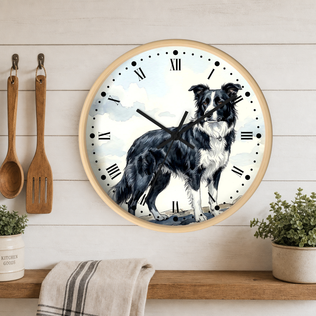 A round wall clock with a light wood frame hangs on a white wood-paneled kitchen wall above a wooden shelf. The clock face features a black and white dog illustration over a soft blue sky background with white Roman numerals.