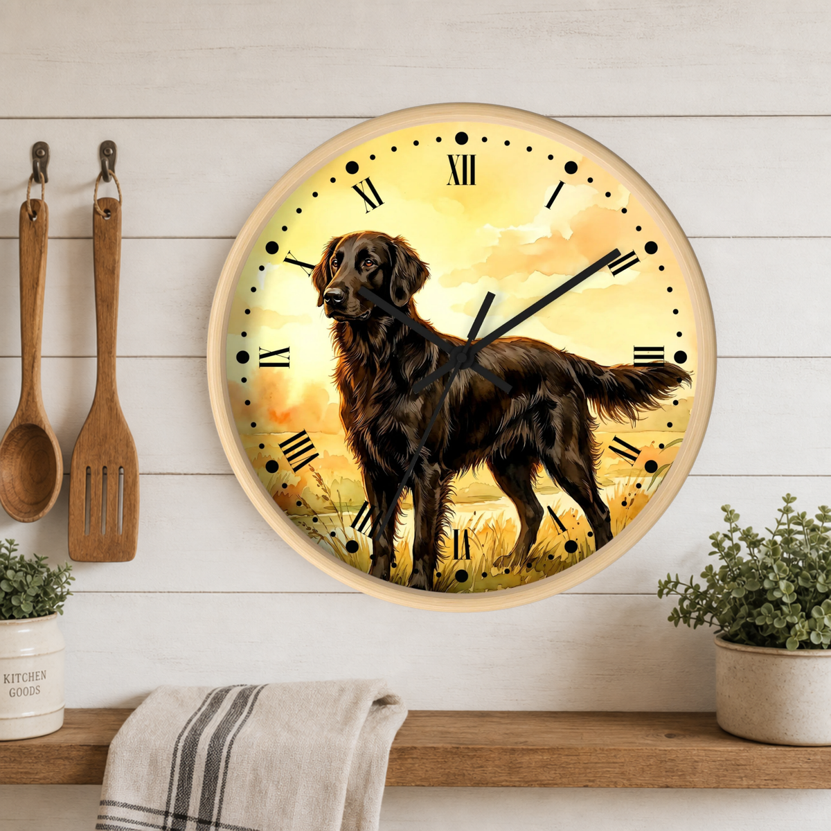 A round wall clock with a light wood frame and Roman numerals, featuring a brown retriever dog standing in a golden field. The clock is mounted on a white wood-paneled wall above a wooden shelf with kitchen utensils, a towel, and potted plants.