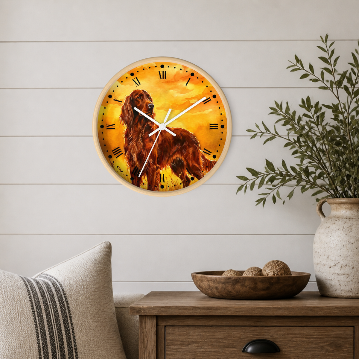 A round wall clock with a warm-toned illustration of a long-haired dog on the face, mounted on a white shiplap wall above a wooden side table with a vase and bowl.