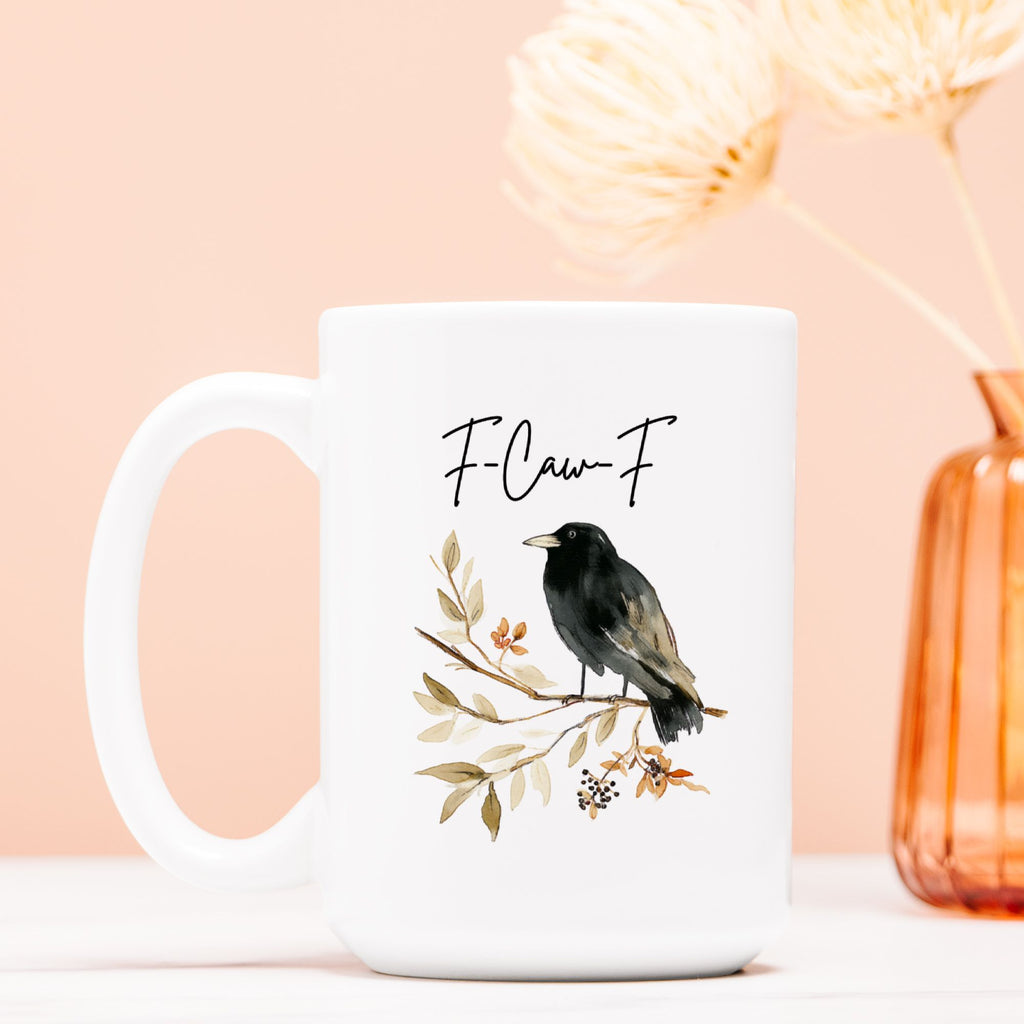 White mug with a bird illustration and 'F-Caw-F' text on a peach background