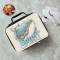 Lunch bag with whale design and 'Spirit' text on a concrete surface with a drink and utensils.