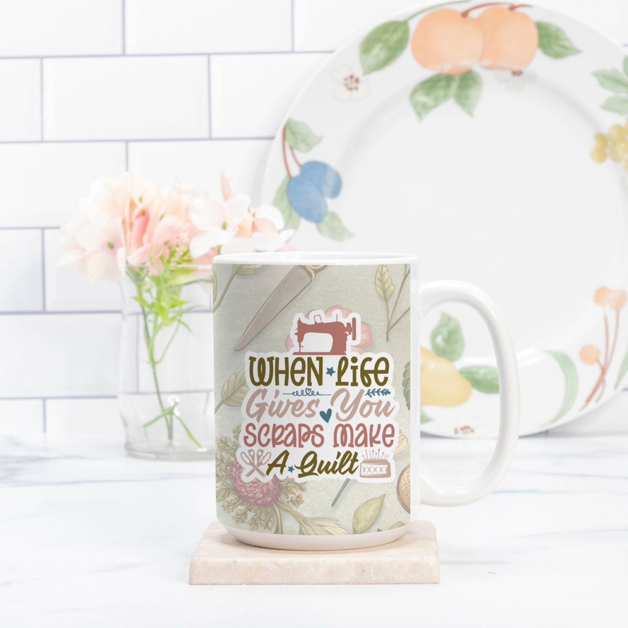 Mug with sewing-themed design and text, placed on a white surface with a decorative plate in the background.