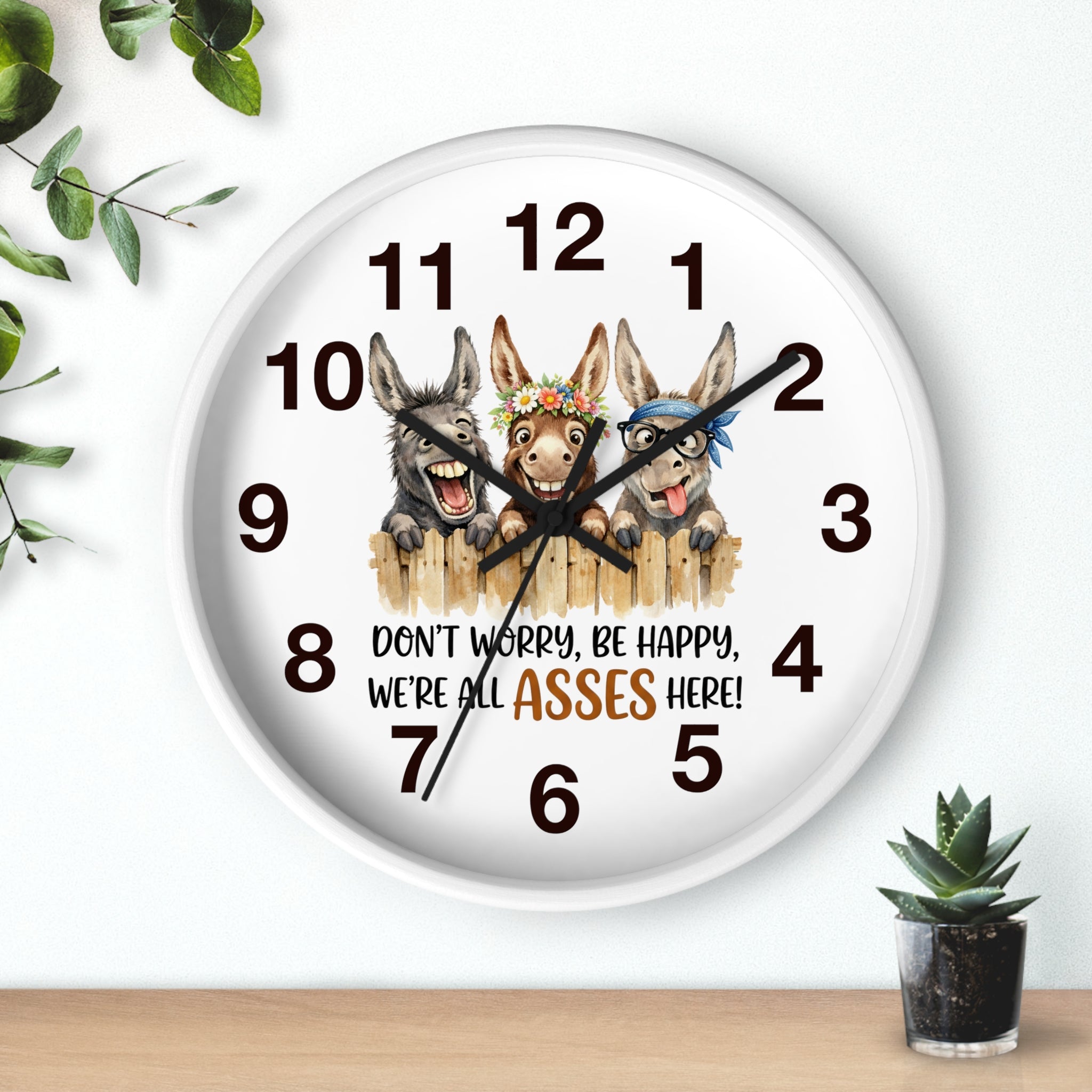 Round white wall clock with cartoon donkeys and humorous text on a white background