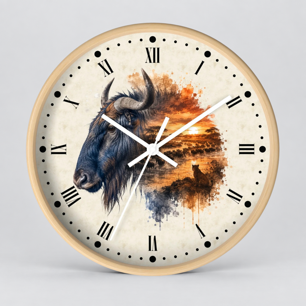 Round wall clock with a light wood frame and a cream-colored face featuring a painted wildebeest and a sunset landscape in warm orange, brown, and blue tones. Black Roman numerals and white clock hands are visible against a light gray studio background.