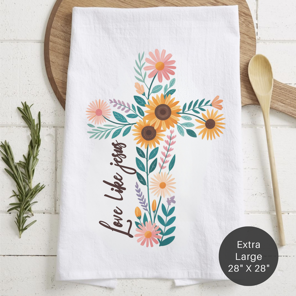Floral designed tea towel with 'Love Like Jesus' text on a wooden surface