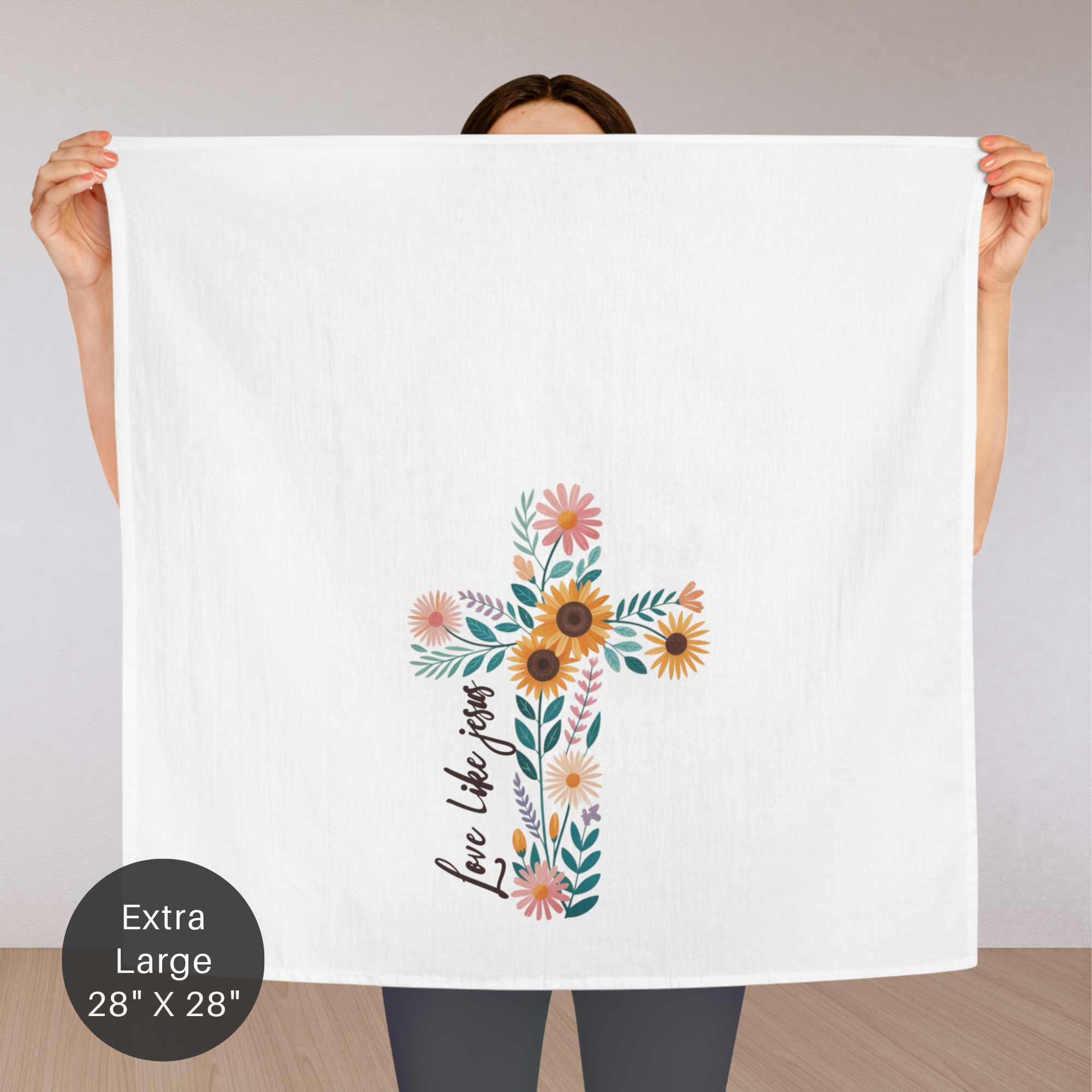 Person holding an extra large white tea towel with a floral cross design and text.