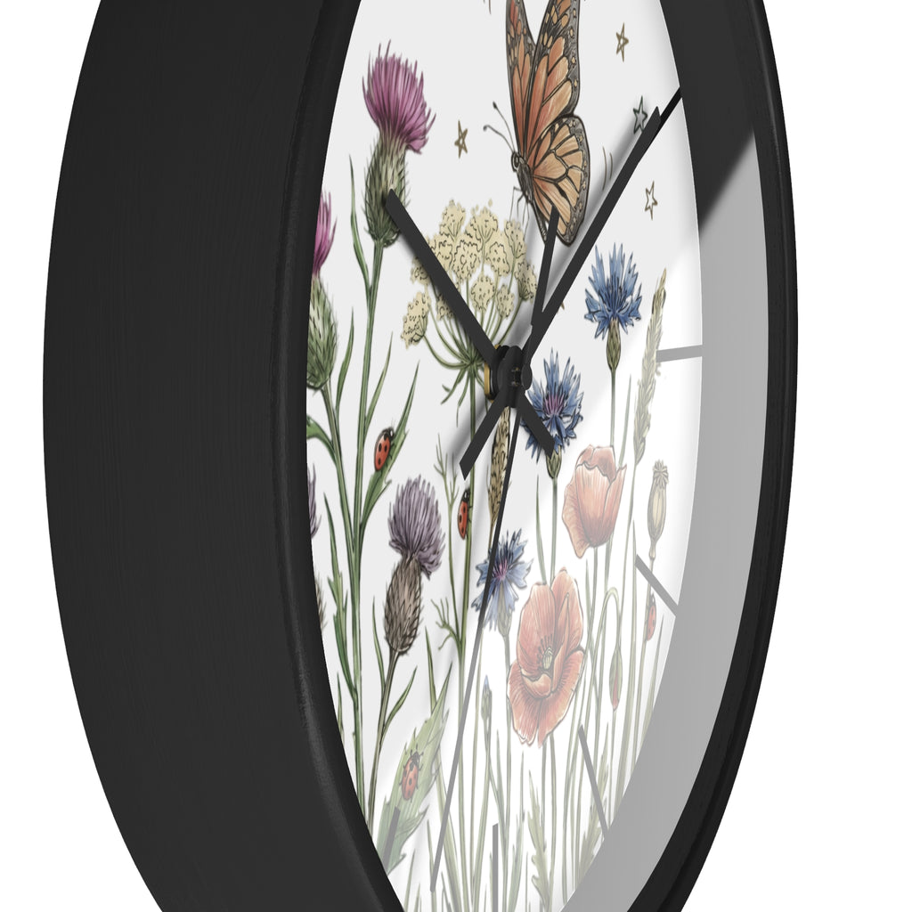 Side view of a a round black wall clock with floral and butterfly design on a white background