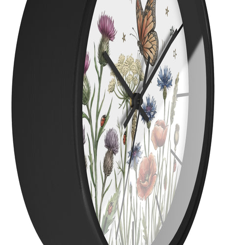 Side view of a a round black wall clock with floral and butterfly design on a white background